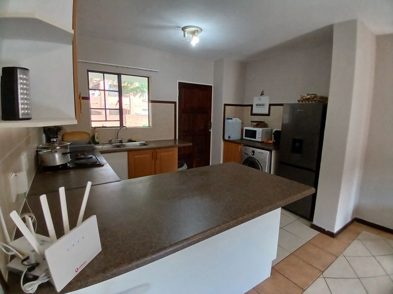 Functional kitchen featuring built-in cabinetry, laminate countertops, tiled backsplash, and ceramic floor tiles, offering a practical layout for daily meal preparation.