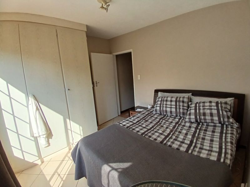 A functional bedroom featuring built-in wardrobes and tiled flooring, offering a neutral canvas for potential interior updates.