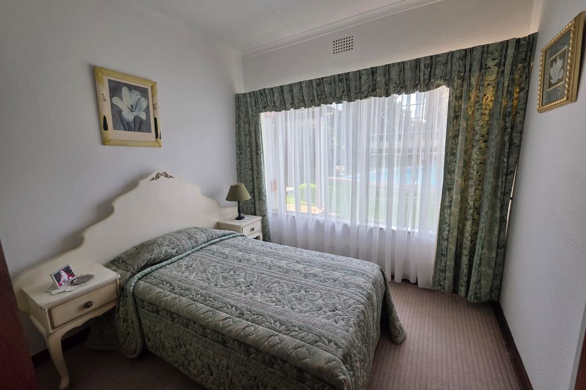 A bedroom featuring carpeted flooring, a large window with curtains, and a ceiling vent.