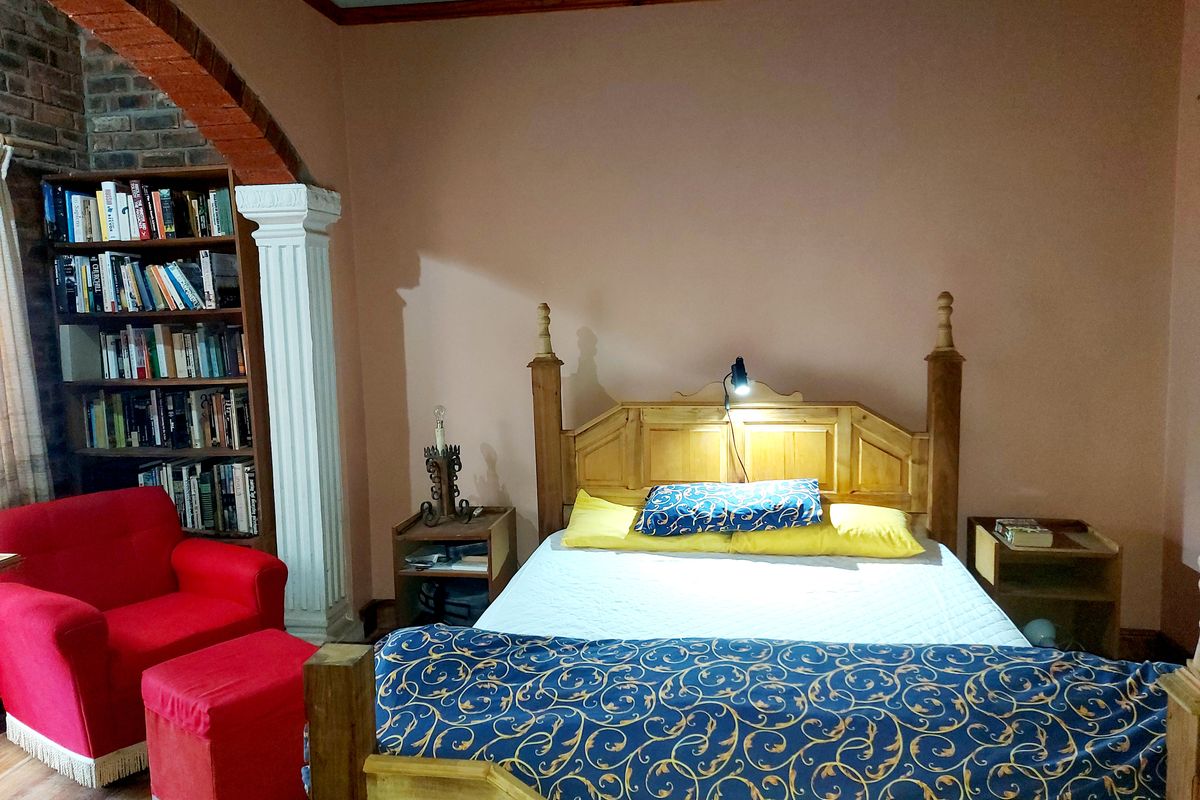 A bedroom featuring a built-in brick archway and decorative column, with wooden flooring and a warm color palette.