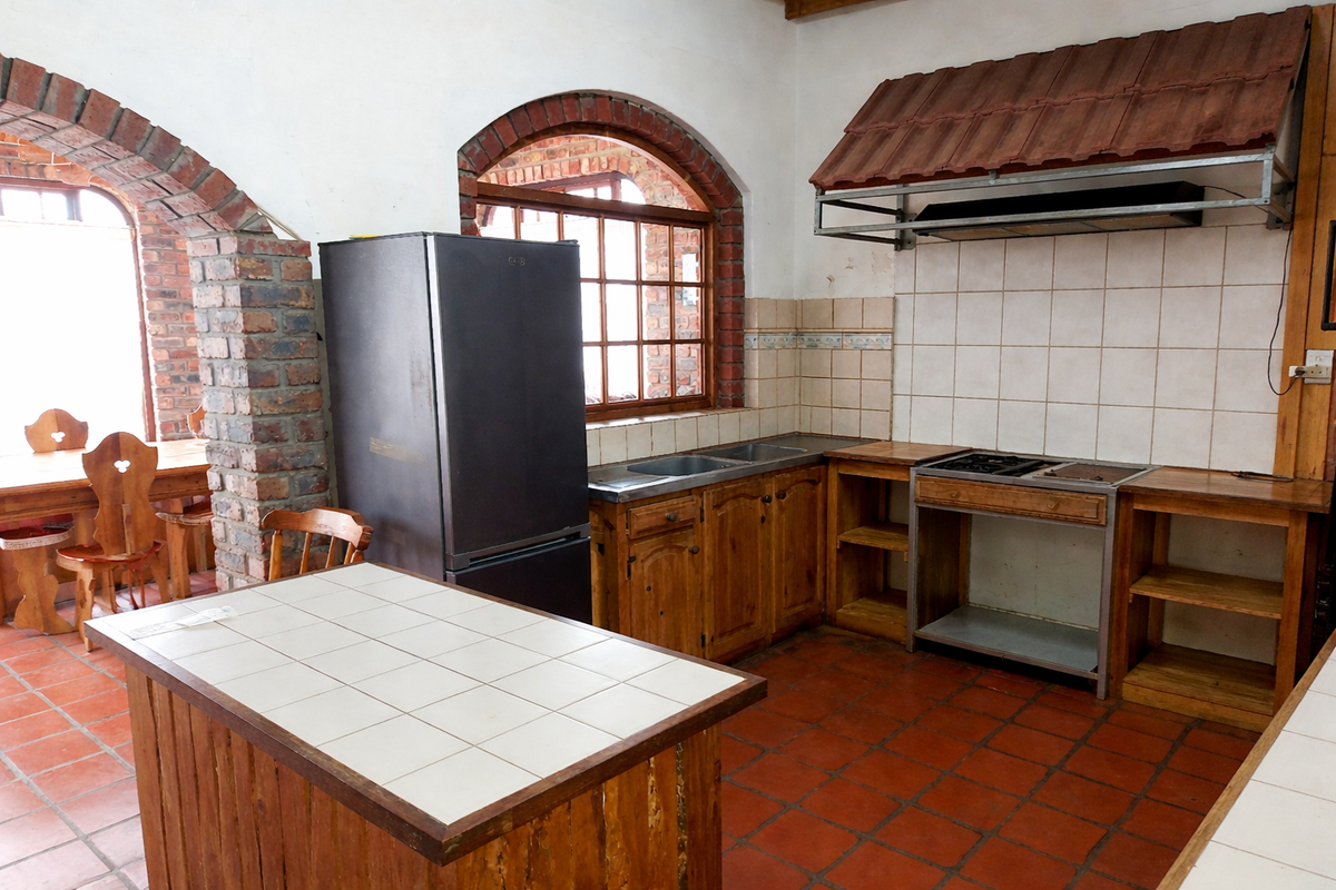 Rustic kitchen featuring exposed brick arches, wooden cabinetry, tiled countertops, and a built-in tiled extractor hood, with an adjacent dining area.