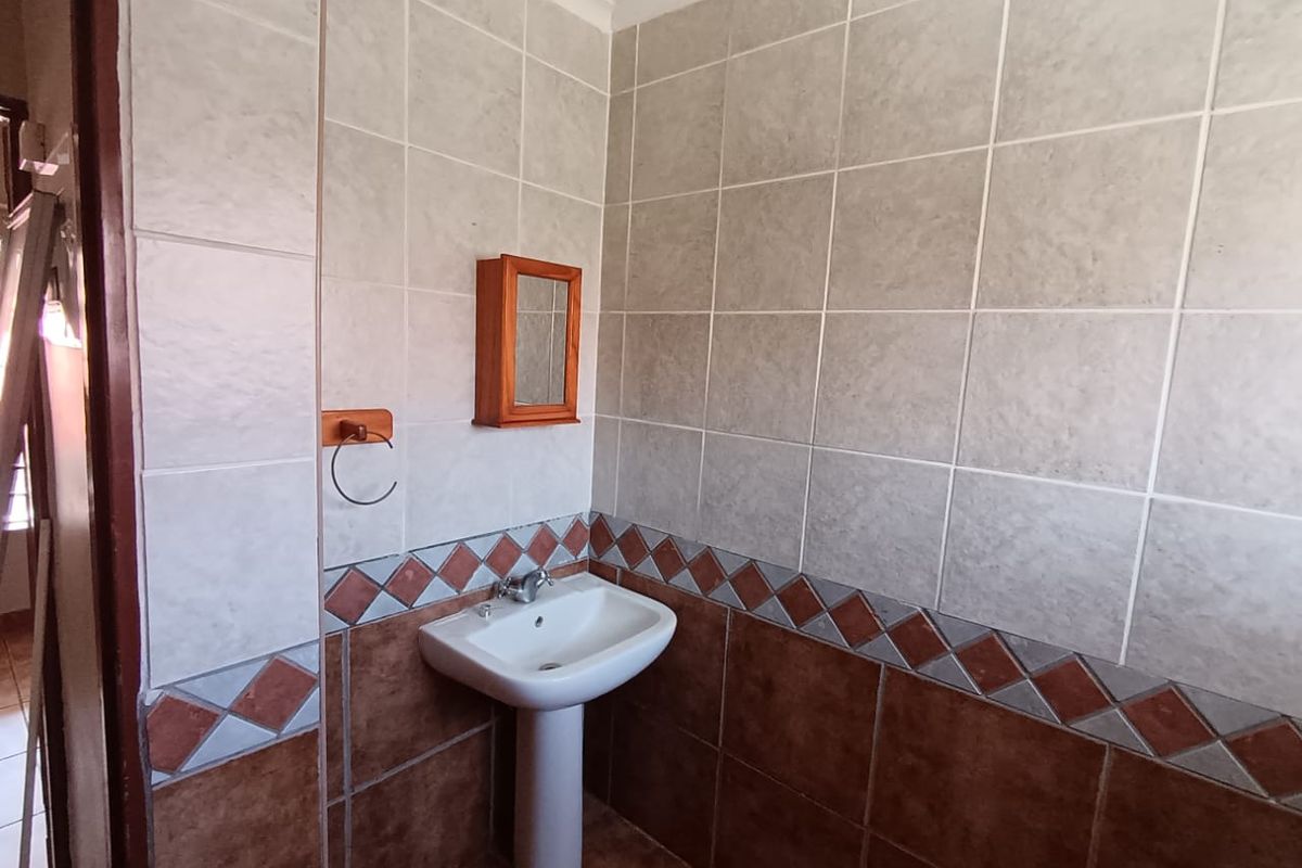 A functional bathroom featuring a pedestal basin with a mixer tap and decorative ceramic wall tiling.