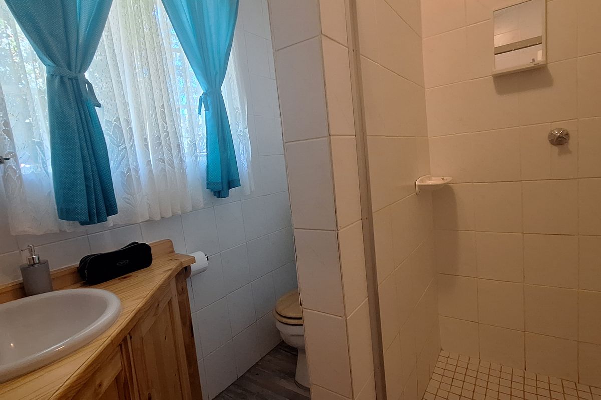 A functional bathroom featuring a built-in wooden vanity with a basin and a separate tiled shower enclosure.