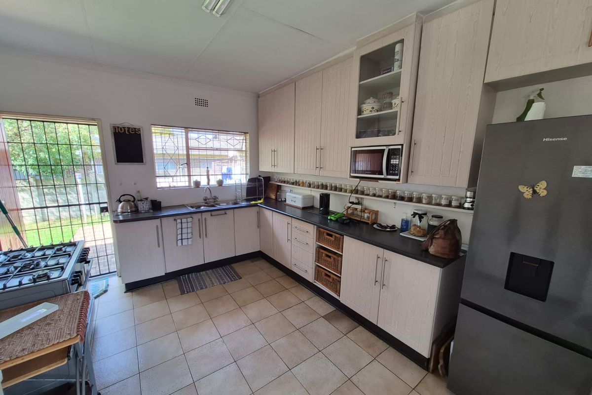 Functional kitchen featuring light-toned cabinetry, dark countertops, integrated microwave, and a double sink, with direct access to the exterior.