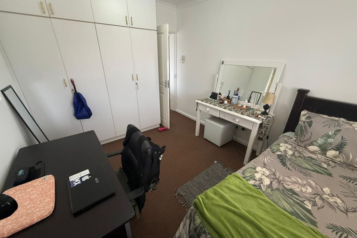 A functional bedroom featuring built-in cupboards and carpeted flooring, offering a practical layout for a comfortable living space.