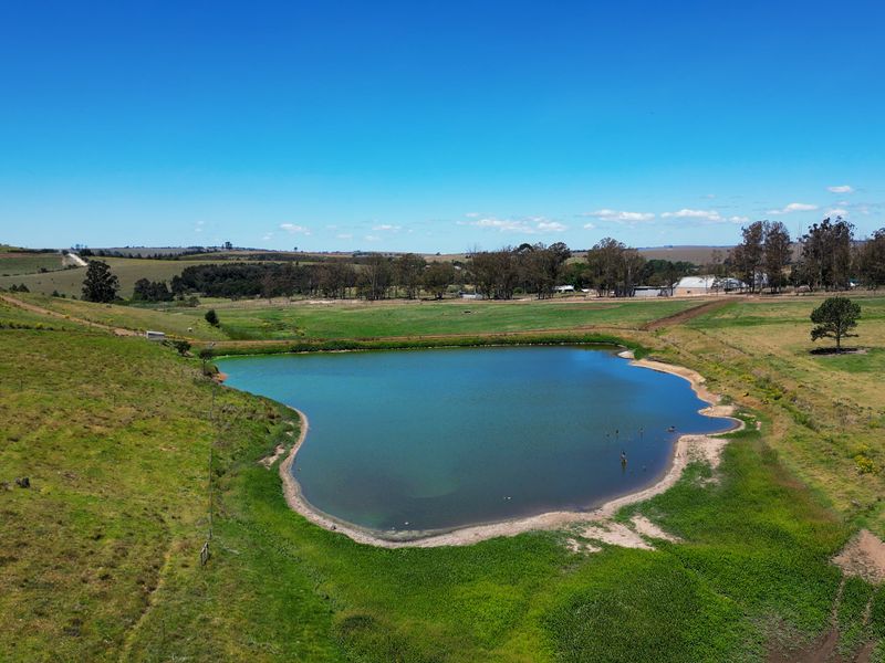 Aerial view of a large farm dam surrounded by open pasture and rolling countryside.