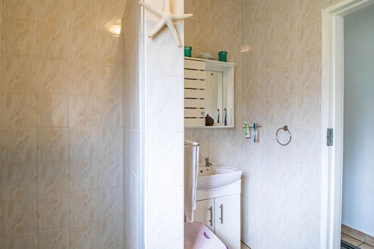A functional bathroom featuring tiled walls, a vanity cabinet with a basin, and a wall-mounted medicine cabinet.