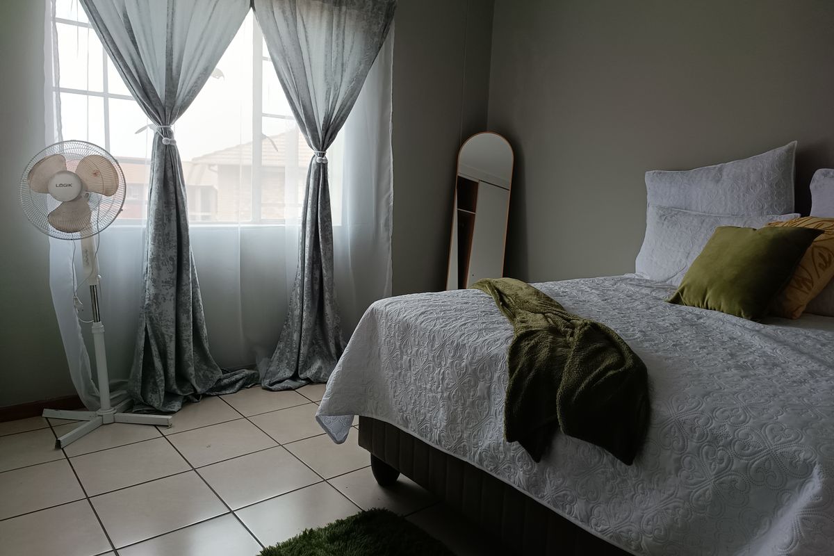 A bedroom featuring tiled flooring and a window with natural light, providing a functional space for rest.