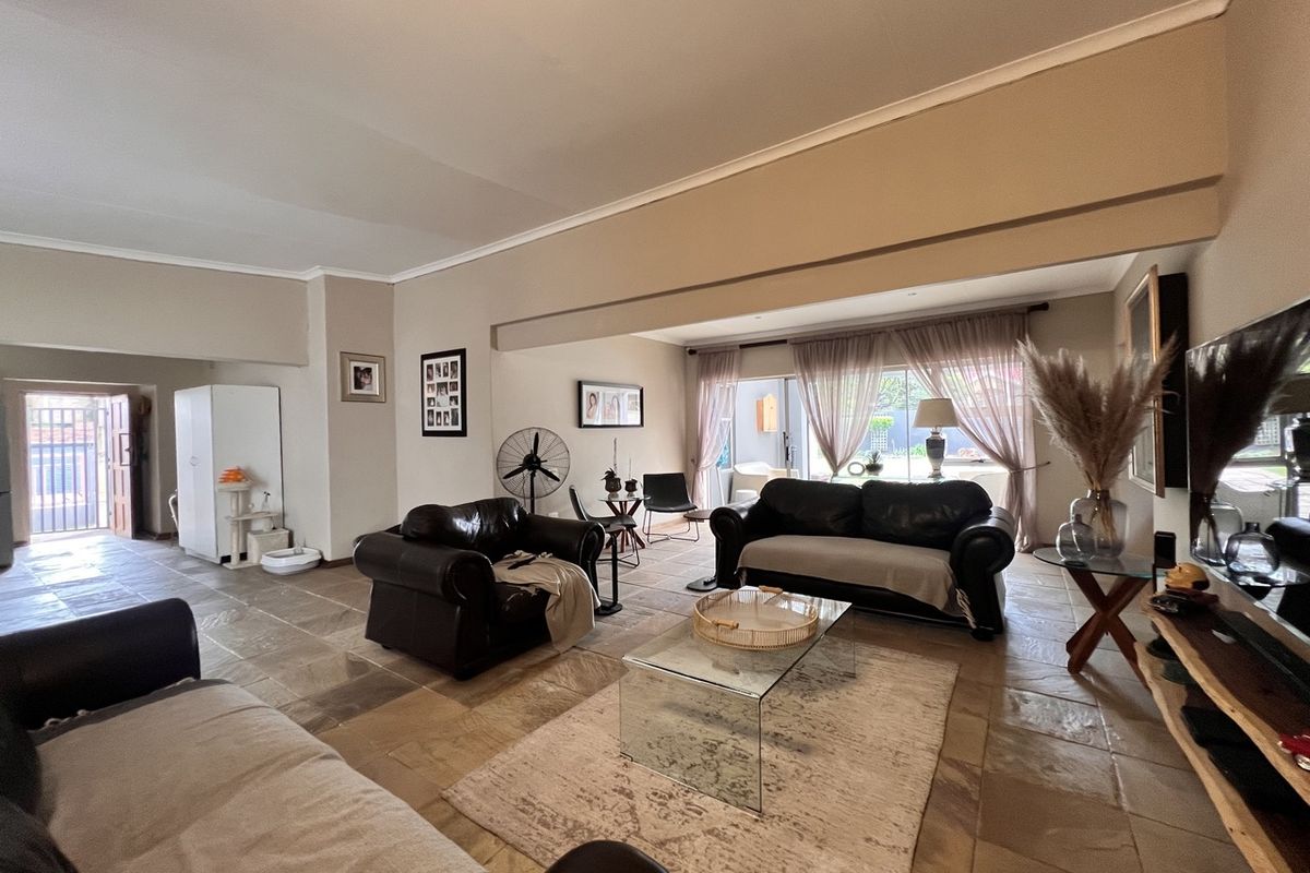 Spacious living room featuring natural stone tile flooring and large sliding glass doors providing access to the outdoor area.