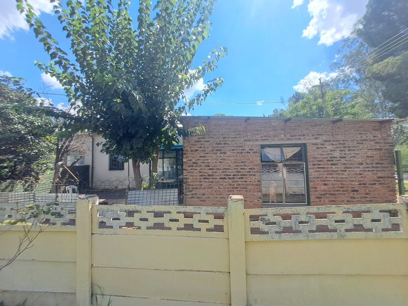 Front view of a residential property featuring an exposed brick facade, steel window frames with security bars, and a precast concrete boundary wall.