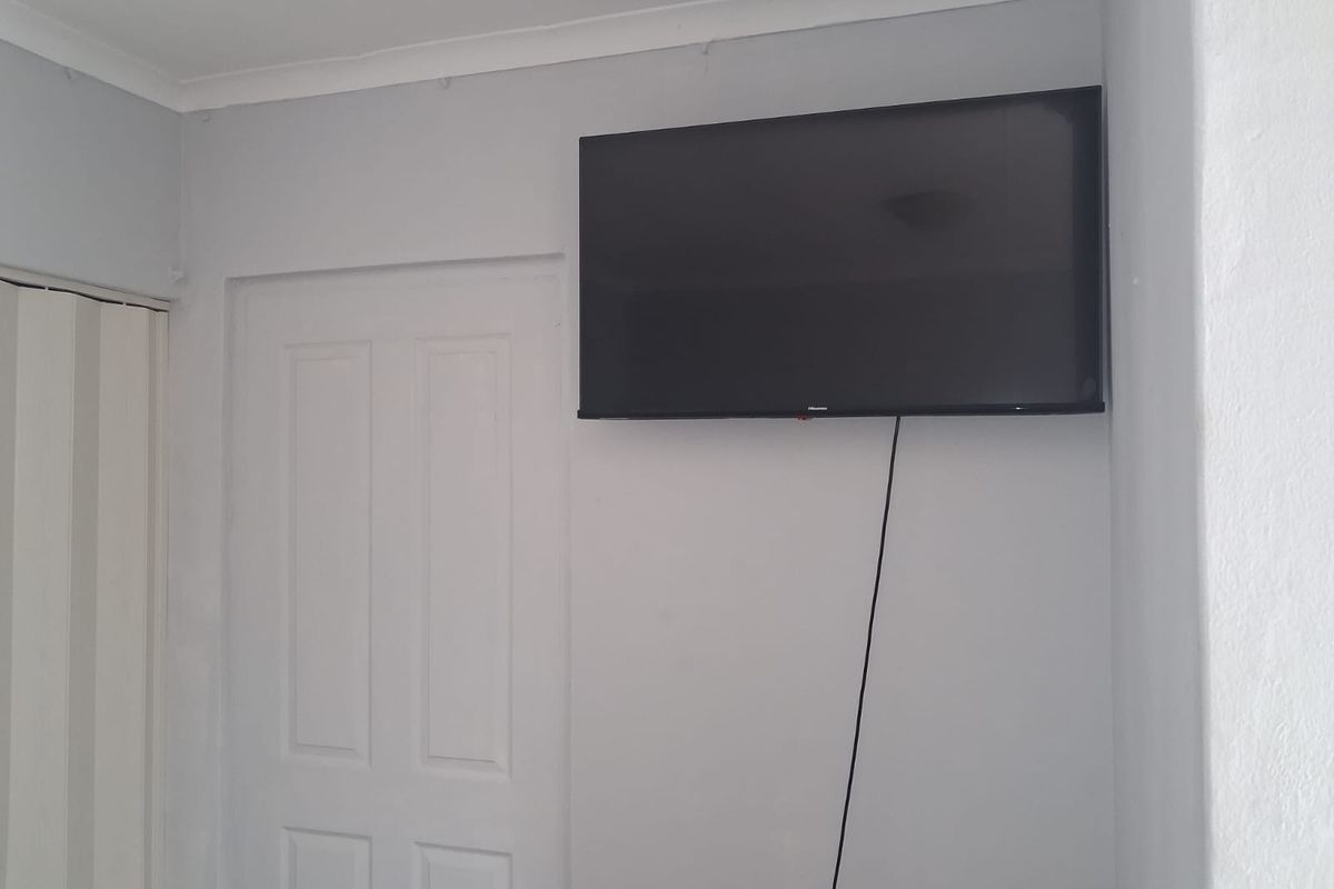 A view of a wall-mounted television in a residential room featuring a standard interior door and neutral wall finishes.