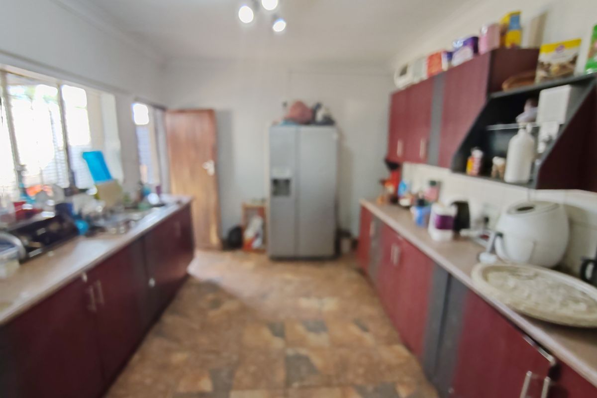 A galley-style kitchen featuring dark cabinetry, laminate countertops, and tiled flooring, requiring updates to improve its overall aesthetic and functionality.