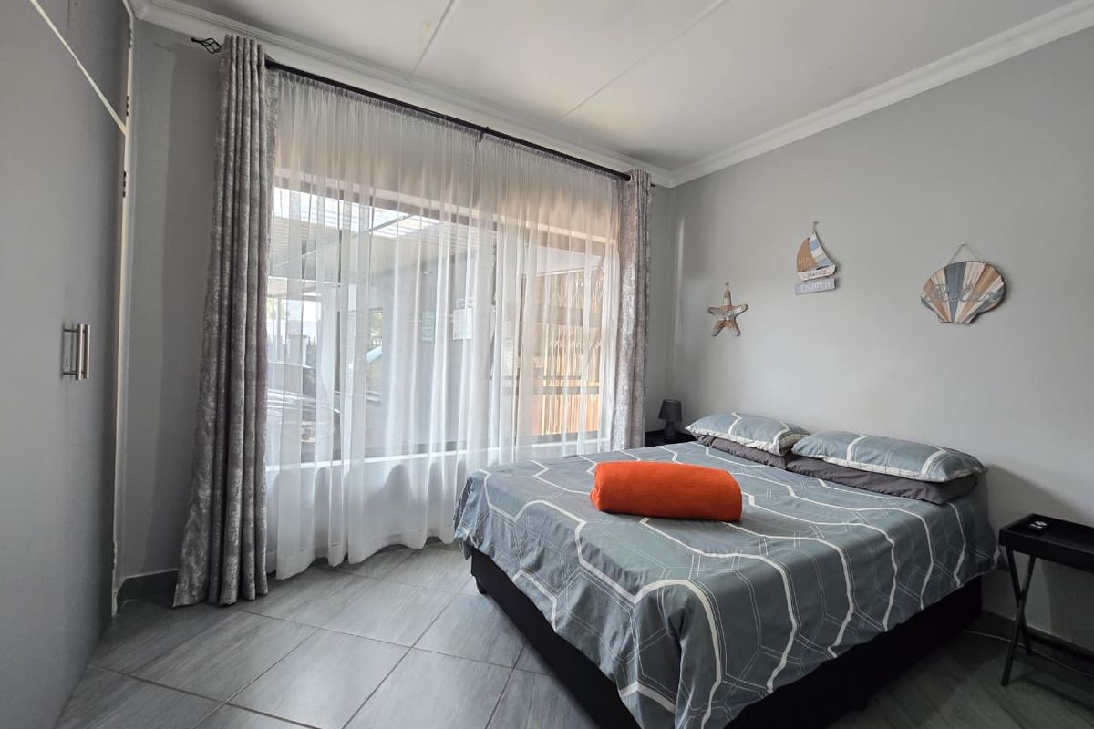 A well-maintained bedroom featuring tiled flooring, a built-in cupboard, and a large window that allows for ample natural light.