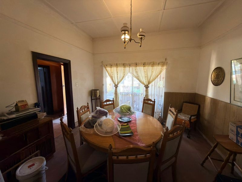 A traditional dining room featuring timber wall paneling, a classic pendant light fixture, and a large window with natural light.