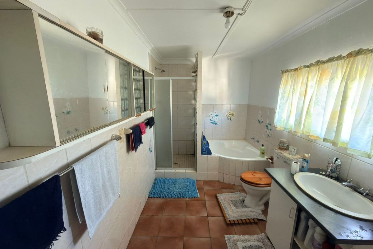 A dated bathroom featuring a corner bathtub, separate shower enclosure, built-in vanity, and tiled finishes throughout.