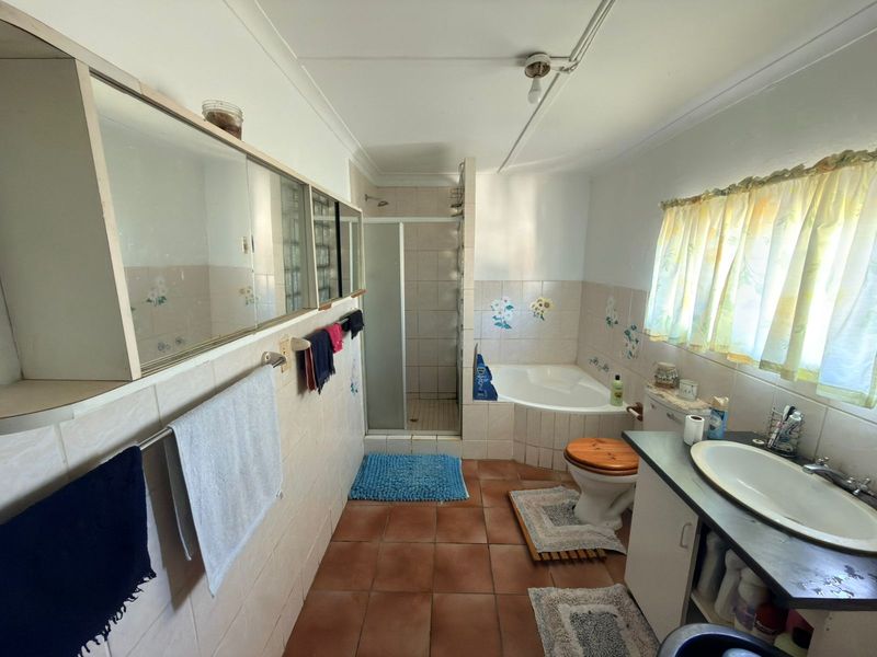 A dated bathroom featuring a corner bathtub, separate shower enclosure, built-in vanity, and tiled finishes throughout.