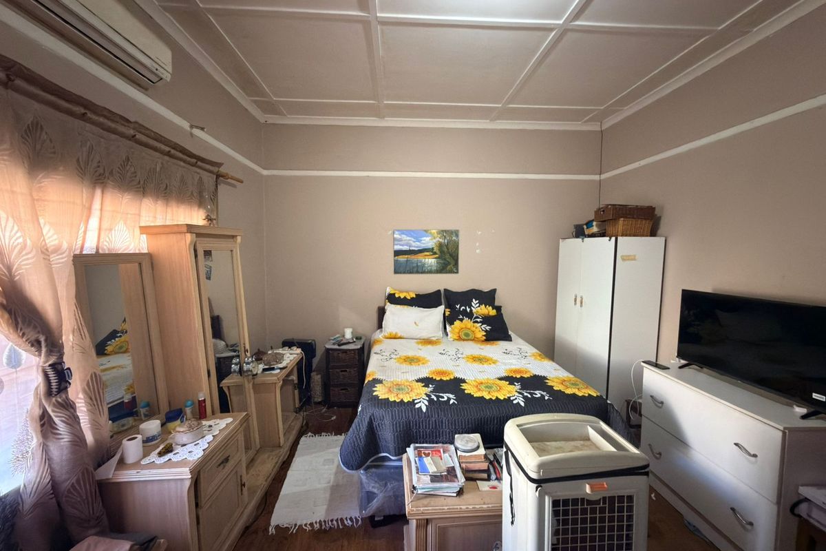 A bedroom featuring timber flooring, a coffered ceiling, and a wall-mounted air conditioning unit.