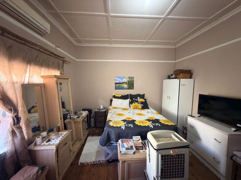 A bedroom featuring timber flooring, a coffered ceiling, and a wall-mounted air conditioning unit.