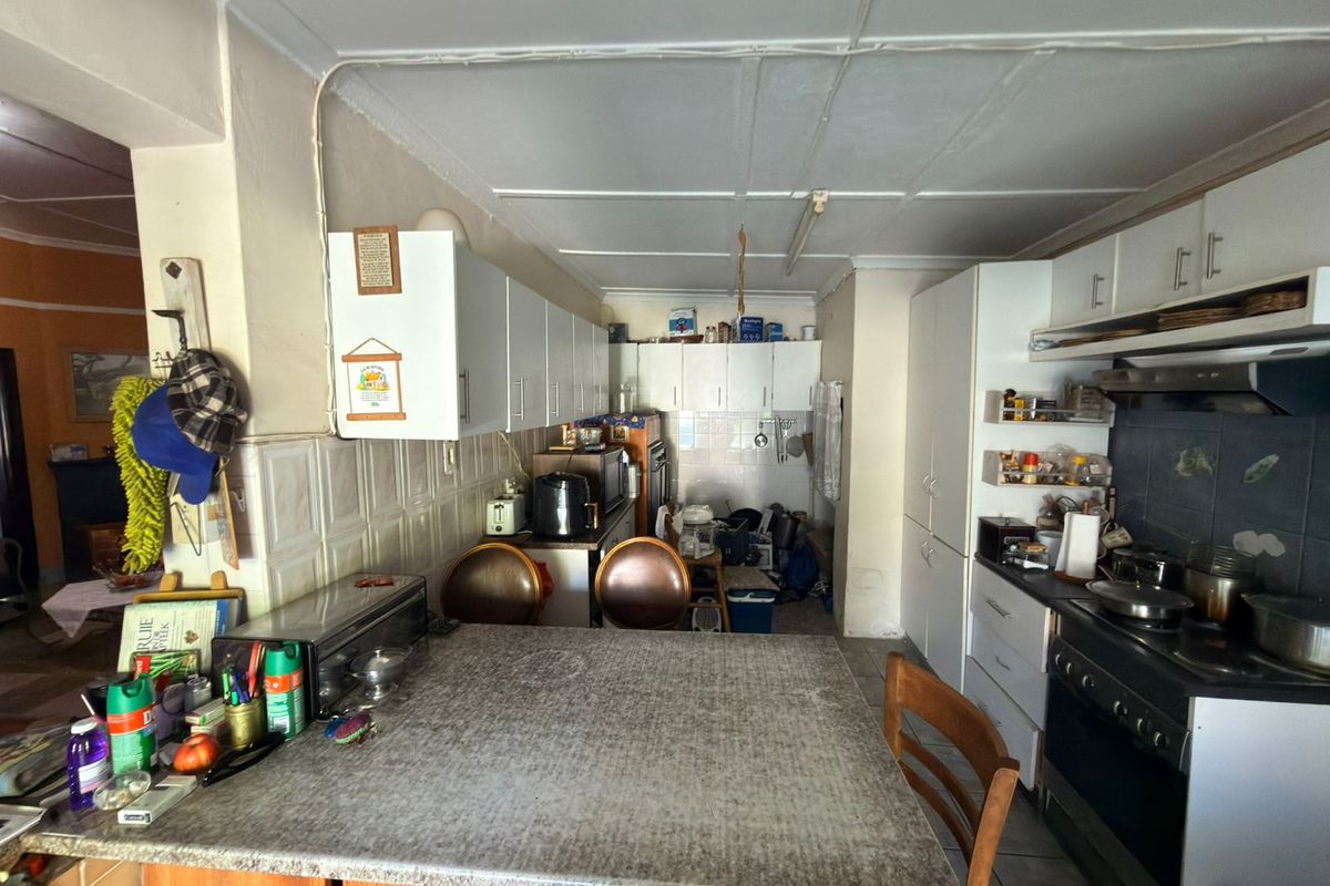 A functional kitchen featuring laminate countertops, ample built-in cabinetry, and a tiled backsplash, offering potential for a modern renovation.