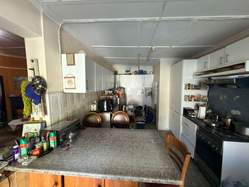 A functional kitchen featuring laminate countertops, ample built-in cabinetry, and a tiled backsplash, offering potential for a modern renovation.