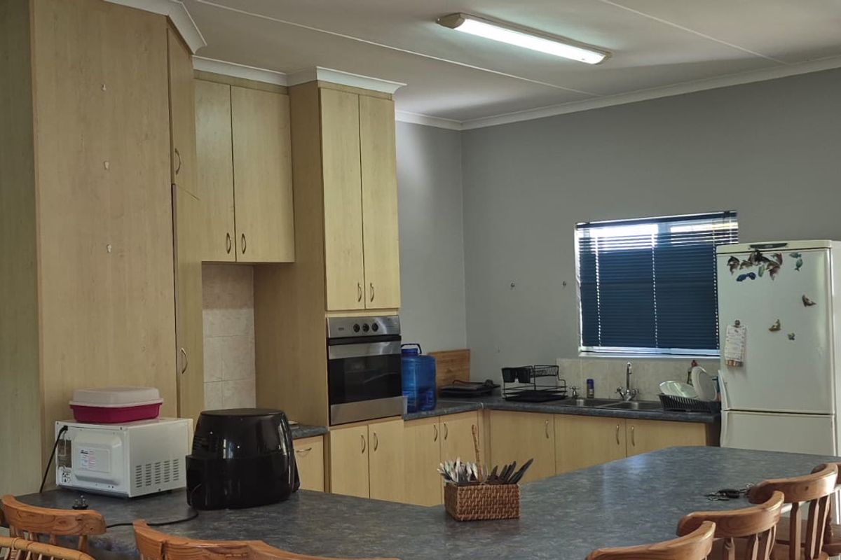 A functional kitchen featuring light wood cabinetry, built-in oven, and a spacious breakfast bar with laminate countertops.