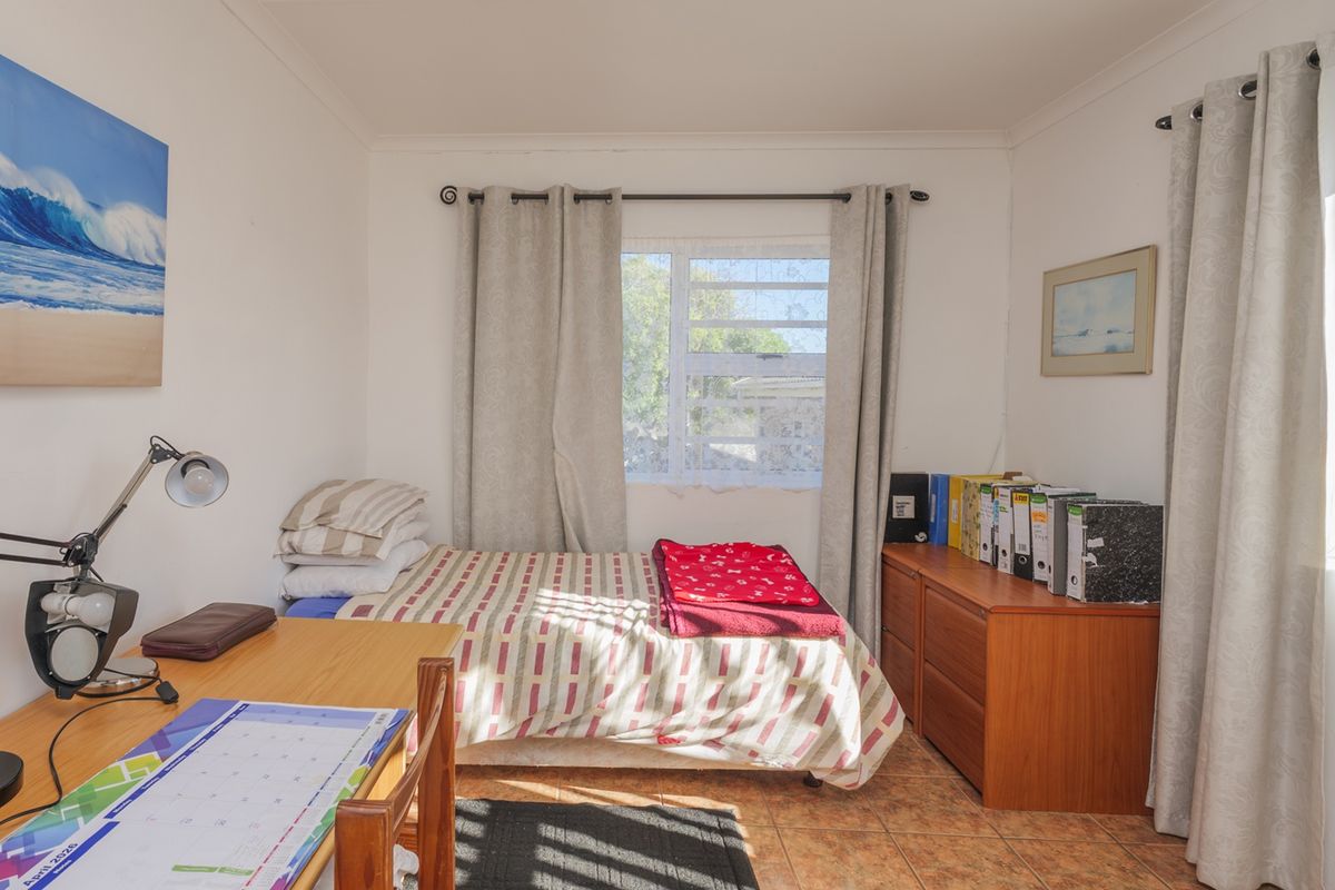 A functional bedroom featuring tiled flooring and natural light through a window with installed curtain rods.