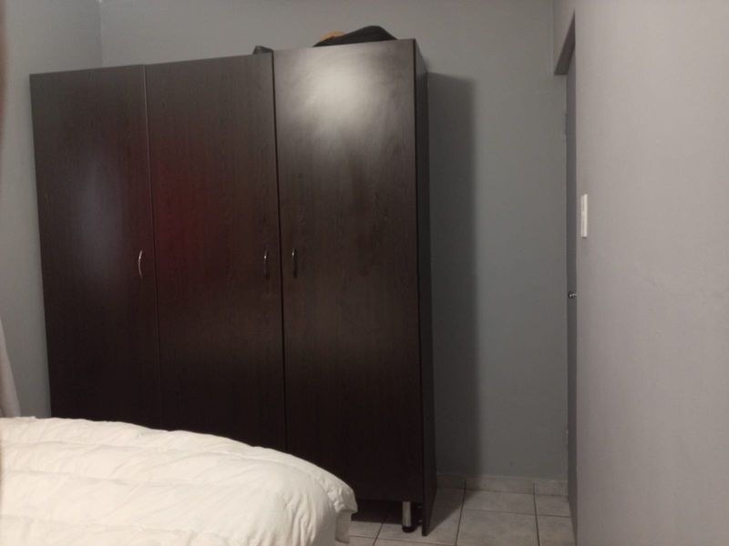 A bedroom featuring tiled flooring and neutral wall paint, providing a functional space for rest.