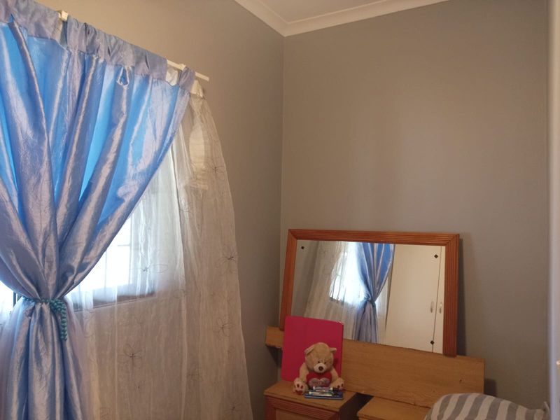 A bedroom featuring neutral wall paint, coving, and a window with curtain fixtures.