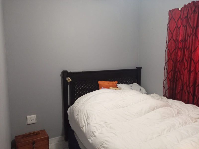 A simple bedroom featuring neutral grey walls and a functional electrical outlet, providing a clean and basic foundation for personal styling.
