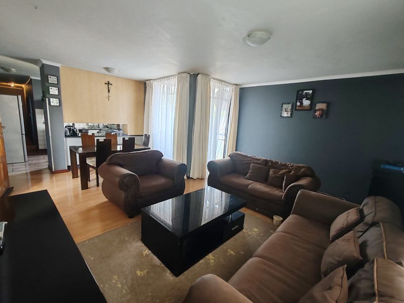 Spacious open-plan living and dining area featuring laminate flooring, neutral wall finishes, and sliding glass doors providing access to the exterior.