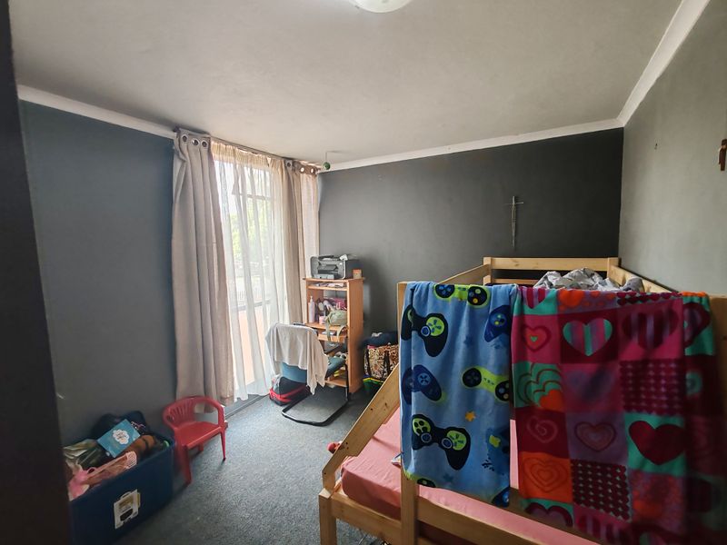 A bedroom featuring dark painted walls, carpeted flooring, and a sliding glass door providing natural light.