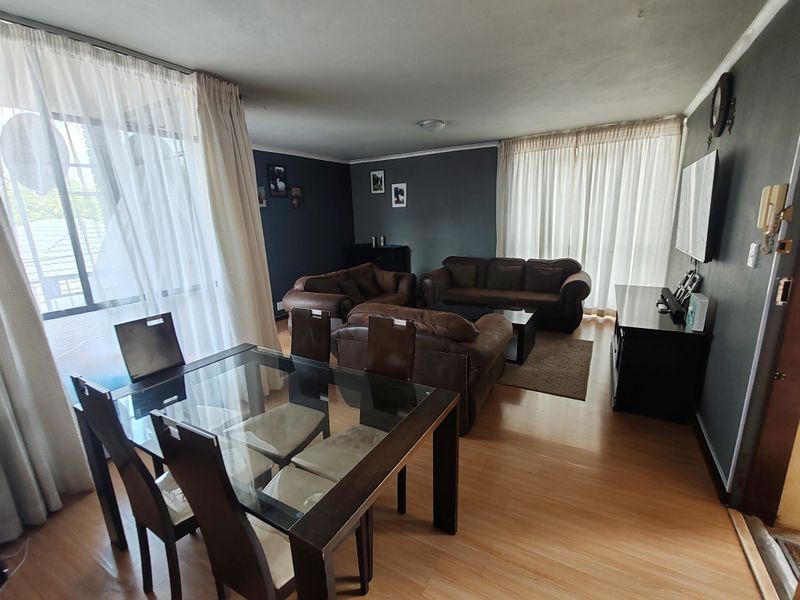 Open-plan living and dining area featuring laminate flooring, large sliding glass doors for natural light, and dark accent walls.