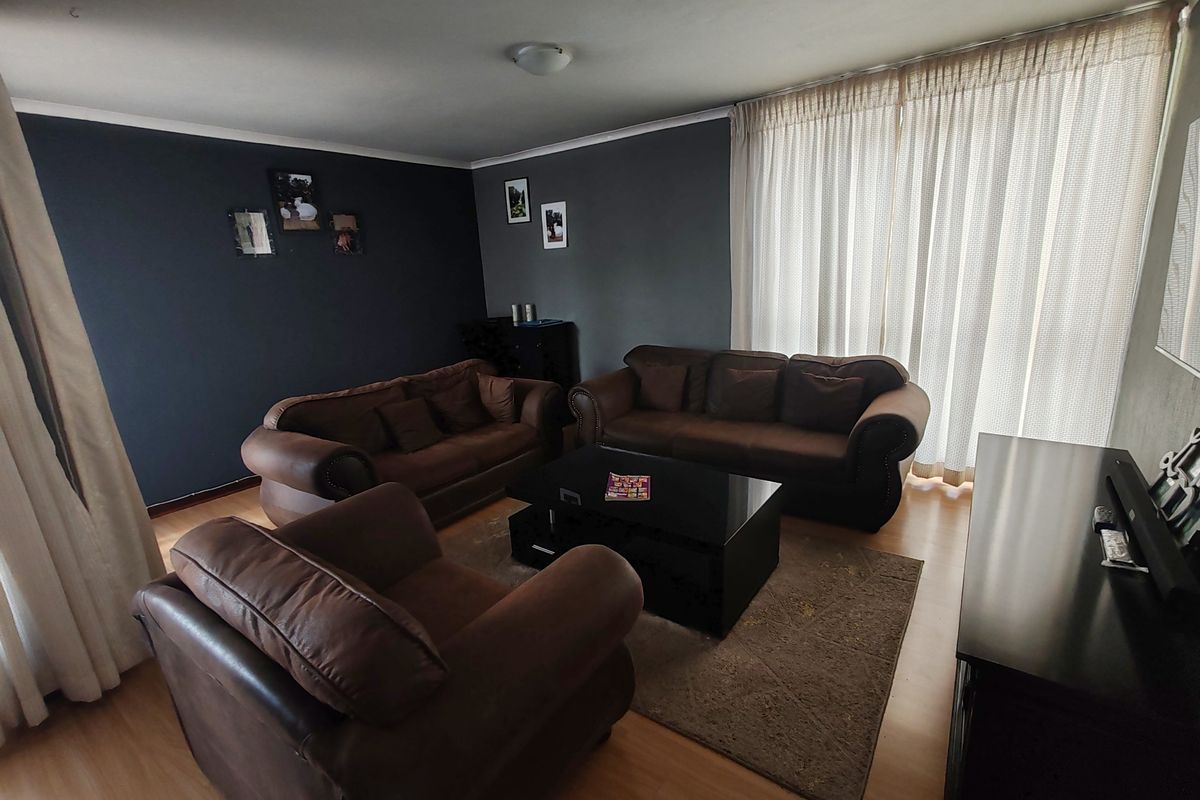 A living room featuring laminate flooring and a large sliding glass door with curtains, providing access to an outdoor area.