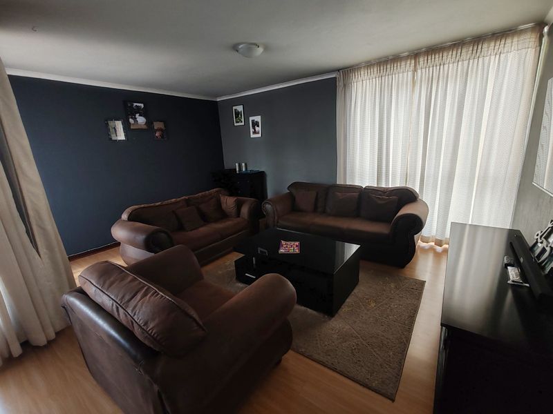 A living room featuring laminate flooring and a large sliding glass door with curtains, providing access to an outdoor area.