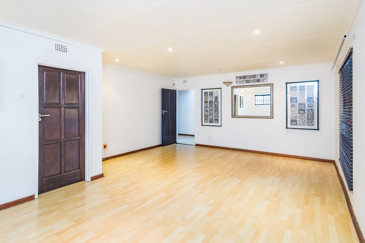 A bright and spacious living area featuring light laminate flooring, recessed downlights, and dark timber doors, offering a clean and neutral canvas.