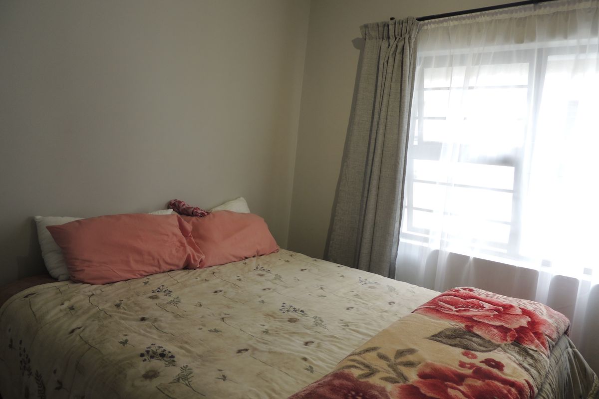 A standard bedroom featuring neutral wall tones and a window with installed curtain rods.