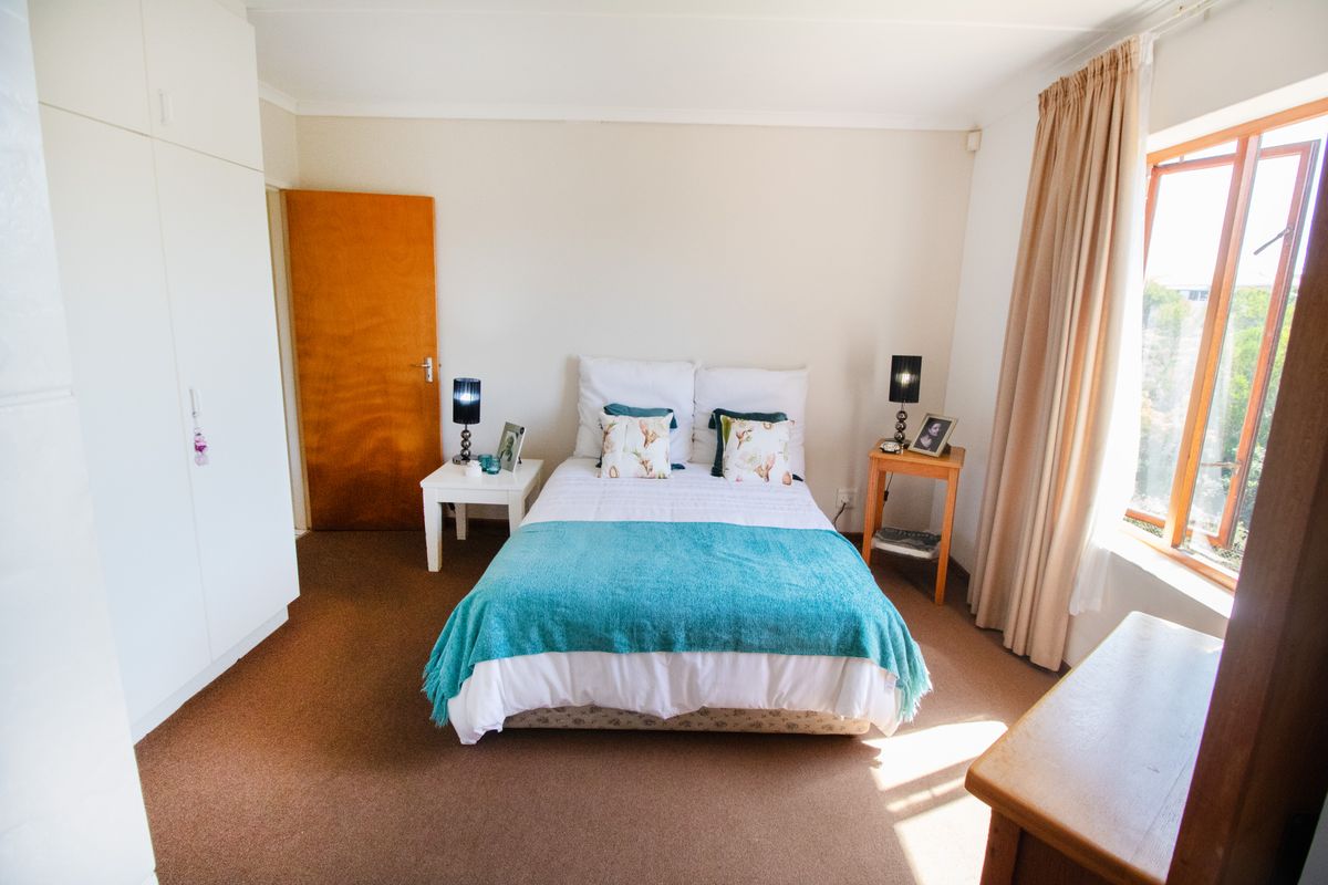 A bedroom featuring built-in cupboards, carpeted flooring, and a window allowing natural light.