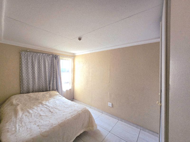 A bedroom featuring tiled flooring, coved ceilings, and a built-in cupboard, requiring cosmetic updates to the wall finishes.