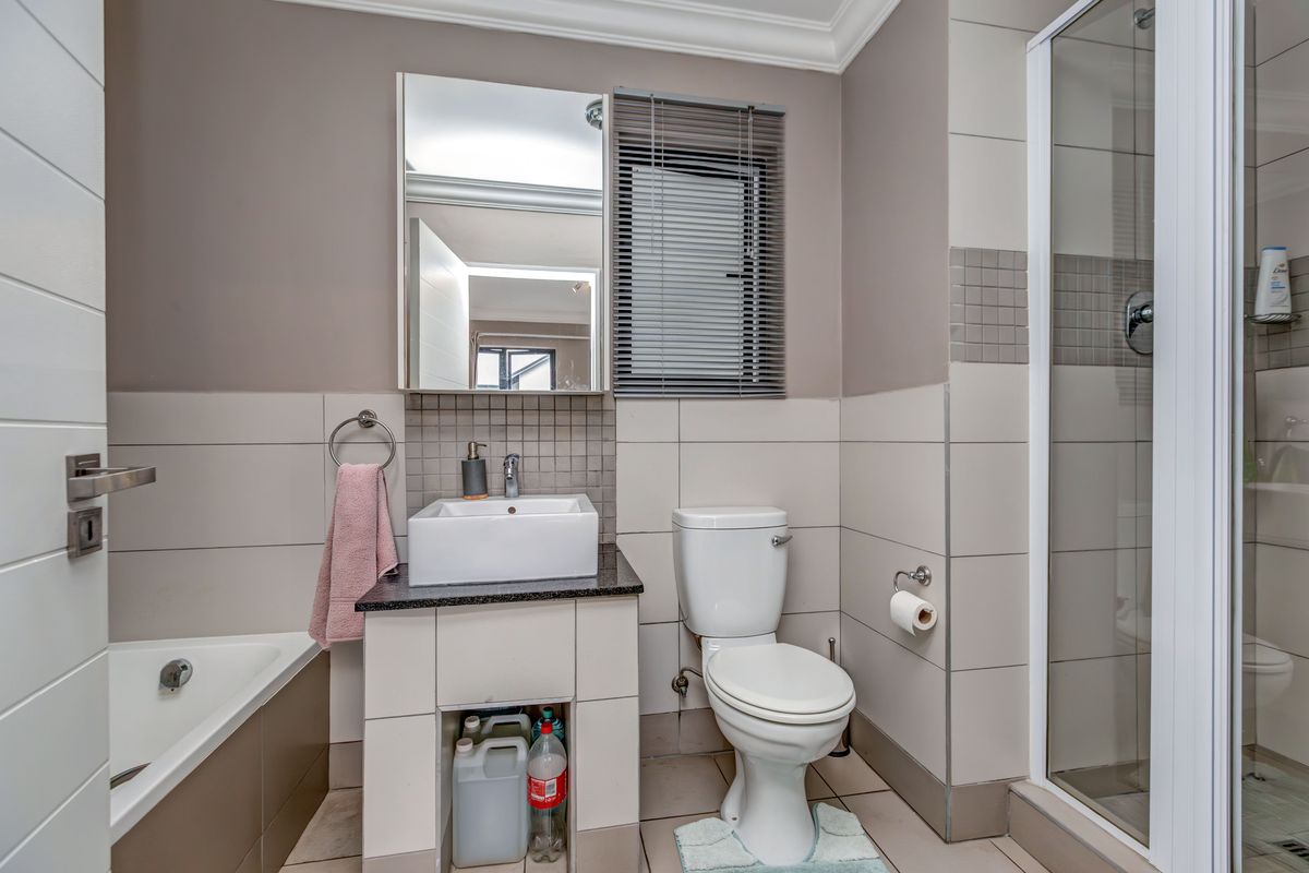 A functional bathroom featuring a vanity with a vessel sink, a separate shower enclosure, and a bathtub with neutral wall tiling.