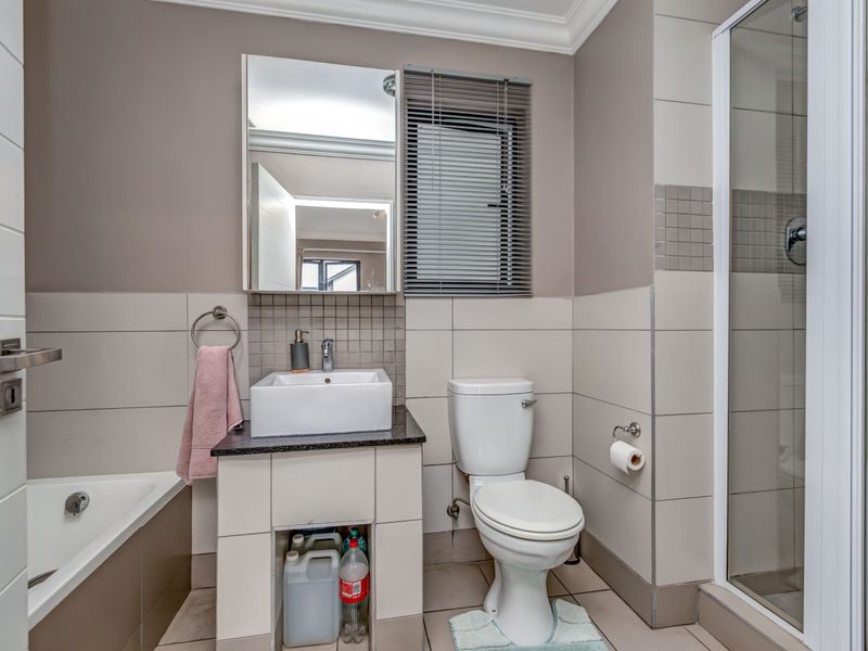 A functional bathroom featuring a vanity with a vessel sink, a separate shower enclosure, and a bathtub with neutral wall tiling.