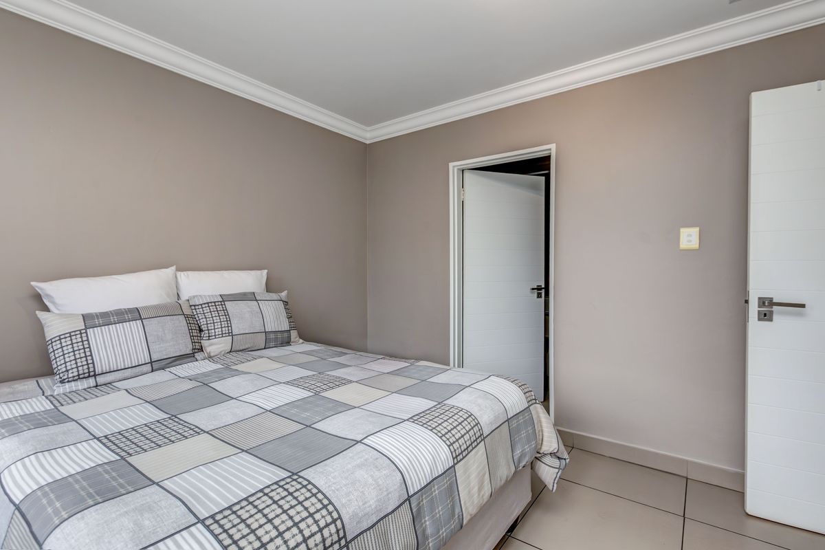 A well-maintained bedroom featuring neutral wall tones, crown molding, tiled flooring, and a modern internal door.