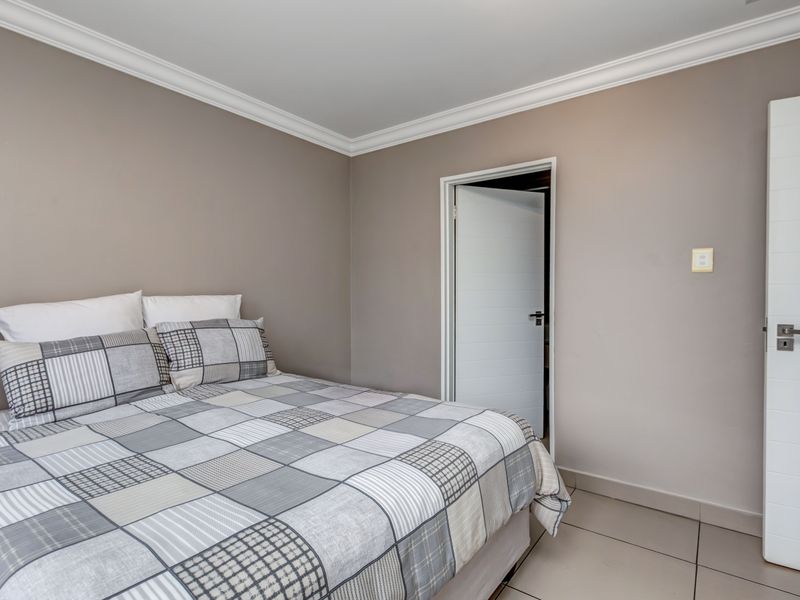A well-maintained bedroom featuring neutral wall tones, crown molding, tiled flooring, and a modern internal door.