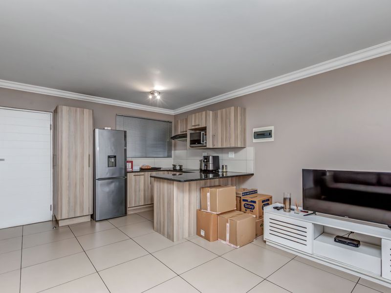 Open-plan kitchen featuring light wood-grain cabinetry, dark granite countertops, and tiled flooring, seamlessly integrated with the living area.