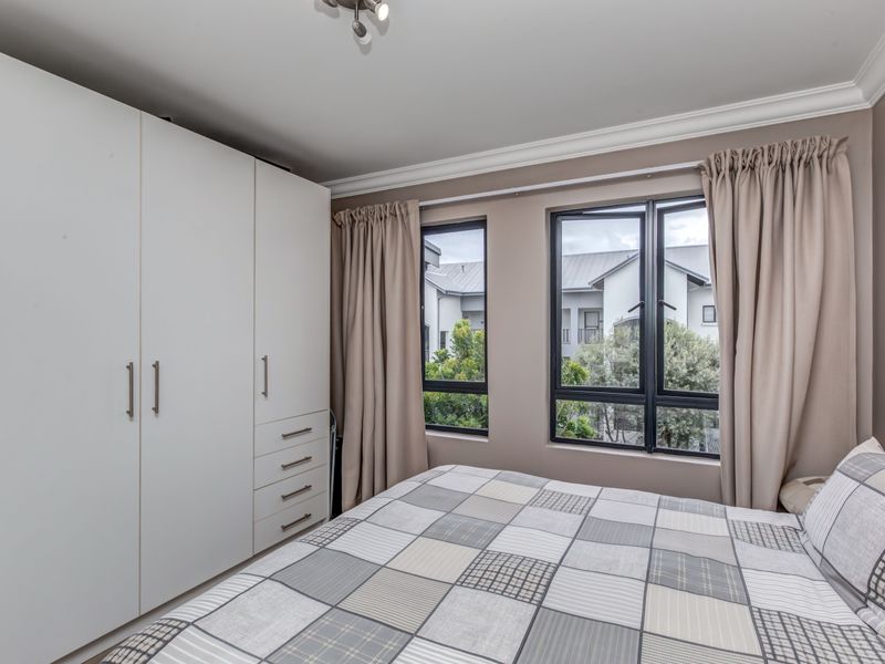 A well-maintained bedroom featuring built-in white cabinetry and large windows with views of the surrounding complex.