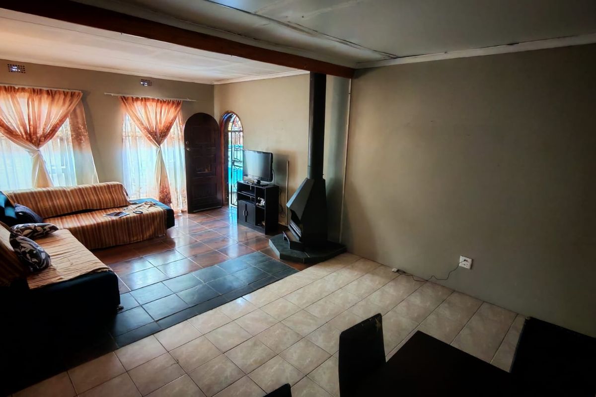 Spacious living area featuring a built-in fireplace, tiled flooring, and direct access to the exterior through an arched doorway.