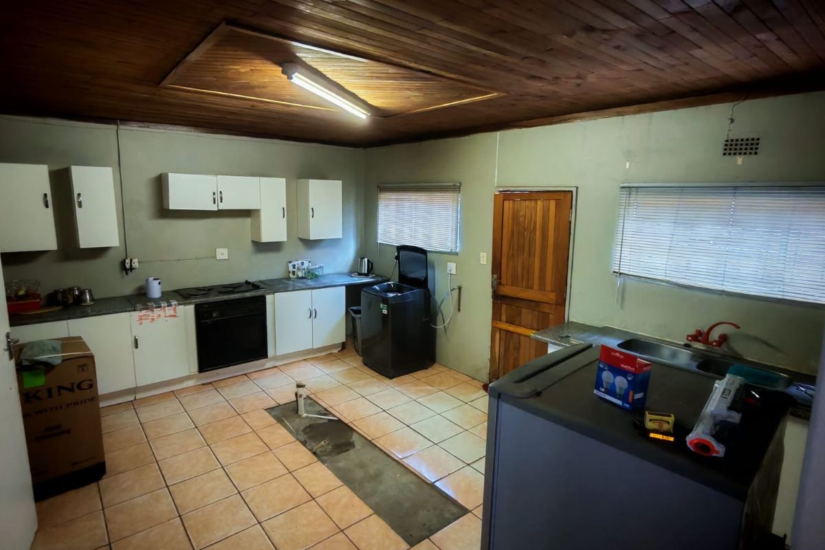 A dated kitchen featuring wooden ceiling paneling, tiled flooring, built-in cabinetry, and an integrated oven and hob.