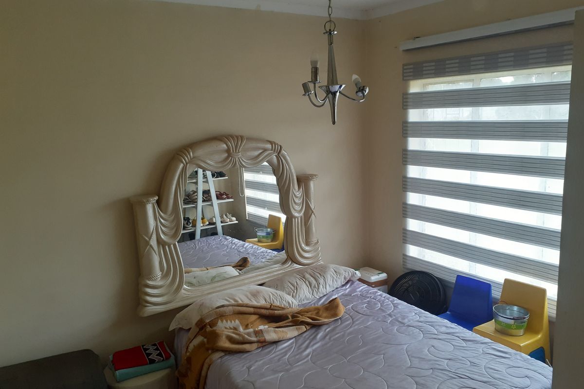 A bedroom featuring a window with modern zebra blinds and a central light fixture.