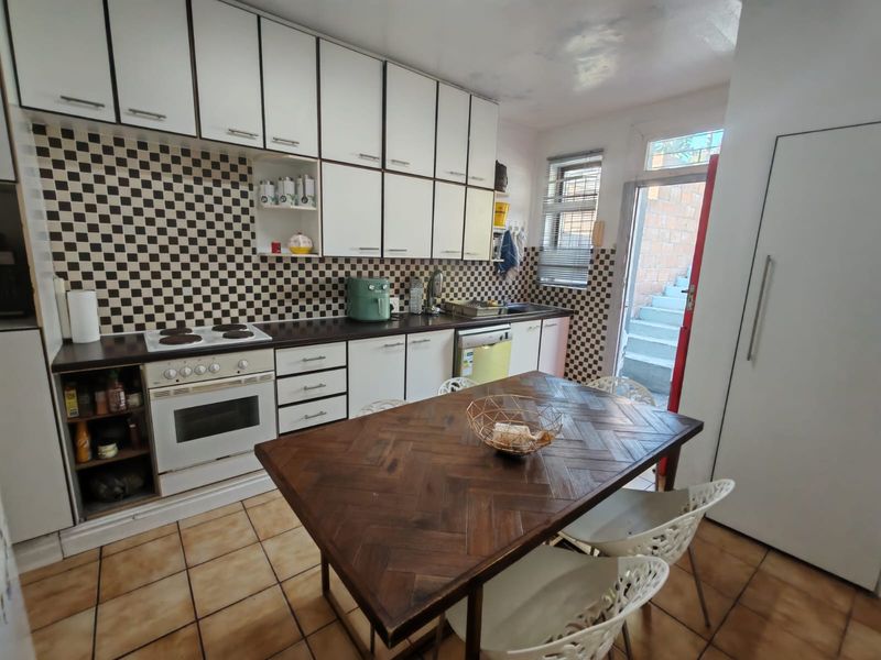 A functional kitchen featuring white cabinetry, a checkered backsplash, tiled flooring, and an integrated stove, with direct access to an outdoor area.