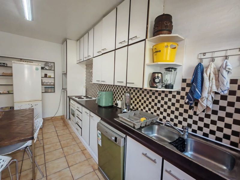 Functional kitchen featuring white cabinetry, dark laminate countertops, a tiled backsplash, and integrated oven and hob, offering a practical layout for daily use.