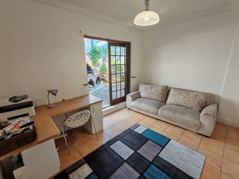 Living room featuring tiled flooring, a built-in desk, and a french door providing direct access to the outdoor patio area.